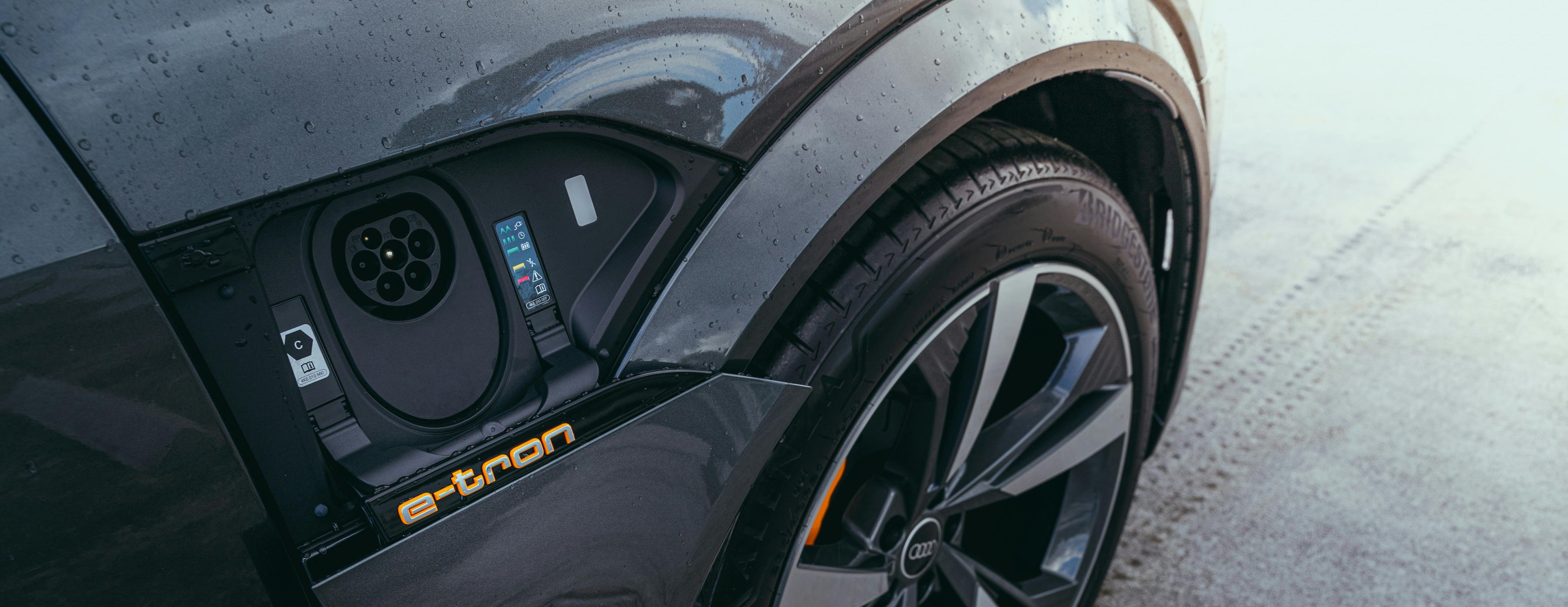 Close-up of a car's charging port with 'e-tron' branding on a road.