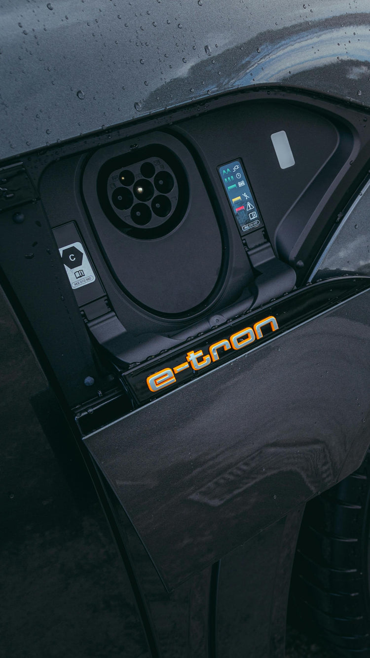 Close-up of a car's charging port with 'e-tron' branding on a road.
